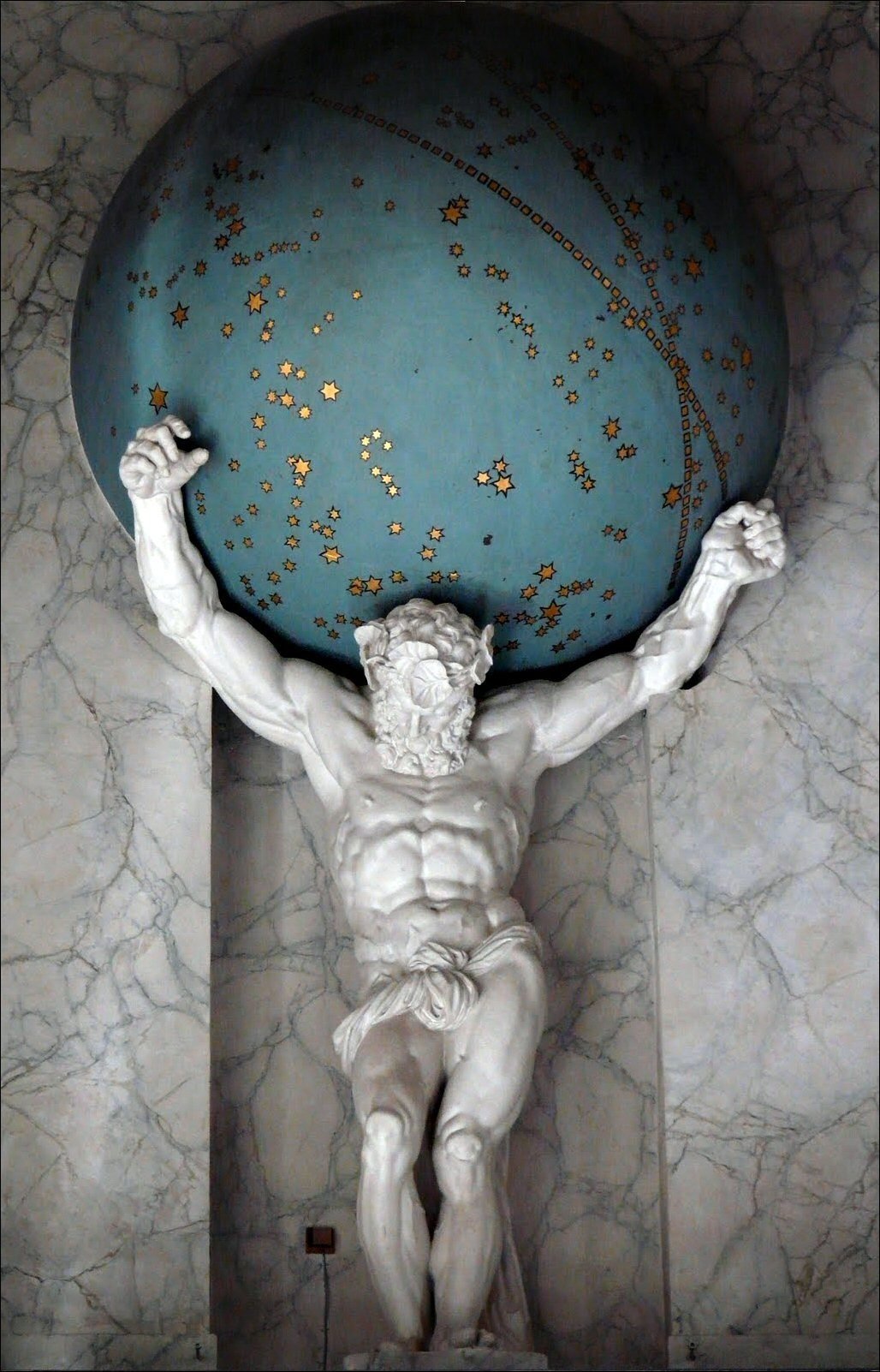 Statue of Jesus Christ with muscular build holding a globe filled with stars and celestial symbols on his shoulders.
